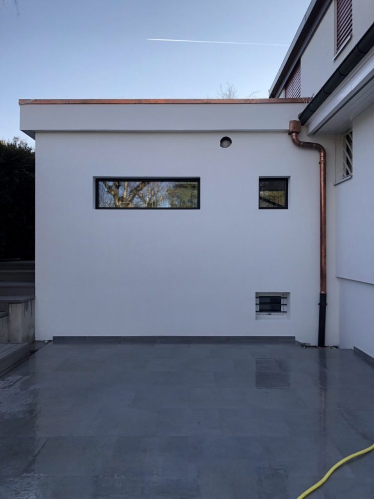 Façade crépie en blanc avec descente d’eau en cuivre