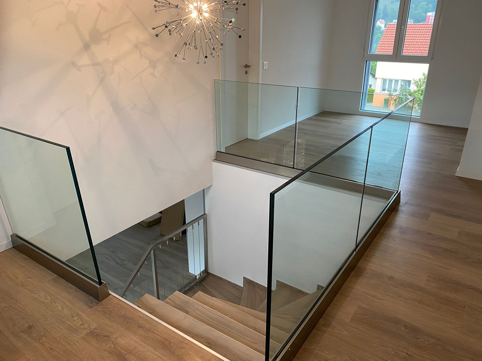 Escalier intérieur, sol clair et garde-corps vitrés.
