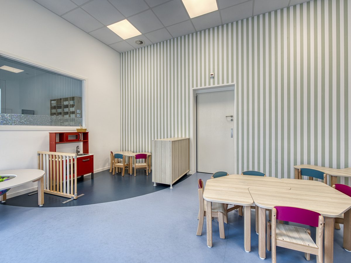 Salle d'activité avec faux-plafond, mur à lattes et mobilier d'enfants