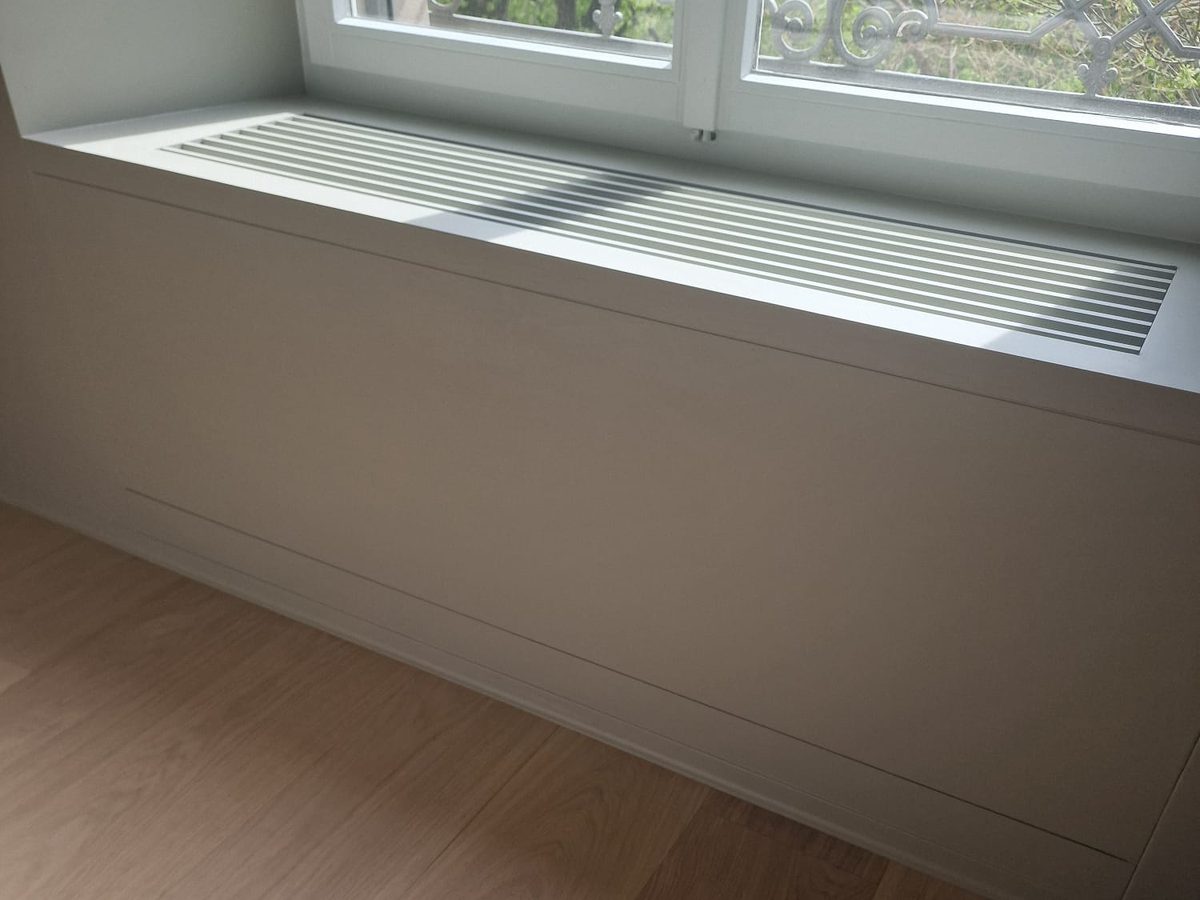 Habillage de radiateur en bois clair sous une fenêtre