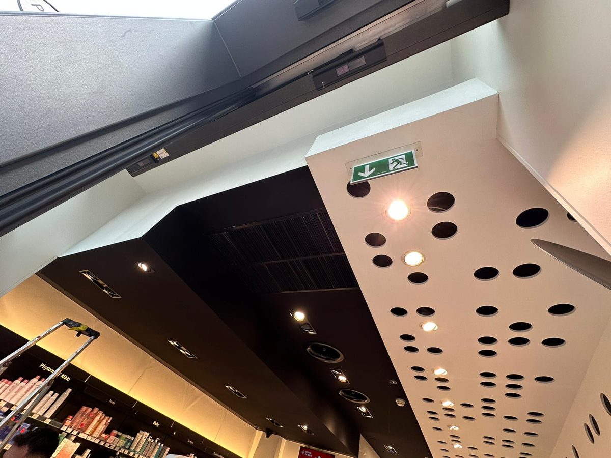 Plafond noir avec panneau métallique perforé et spots dans un commerce